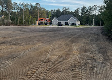 Large, freshly graded and leveled dirt lot in front of a new house