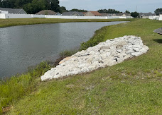 Riprap stone reinforcement along the grassy bank of a pond
